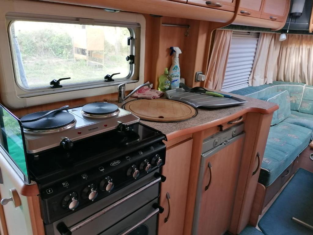Il comprend une cuisine équipée d'une cuisinière et d'un évier. dans l'établissement Caravane des prés, à Saint-Georges-de-Didonne