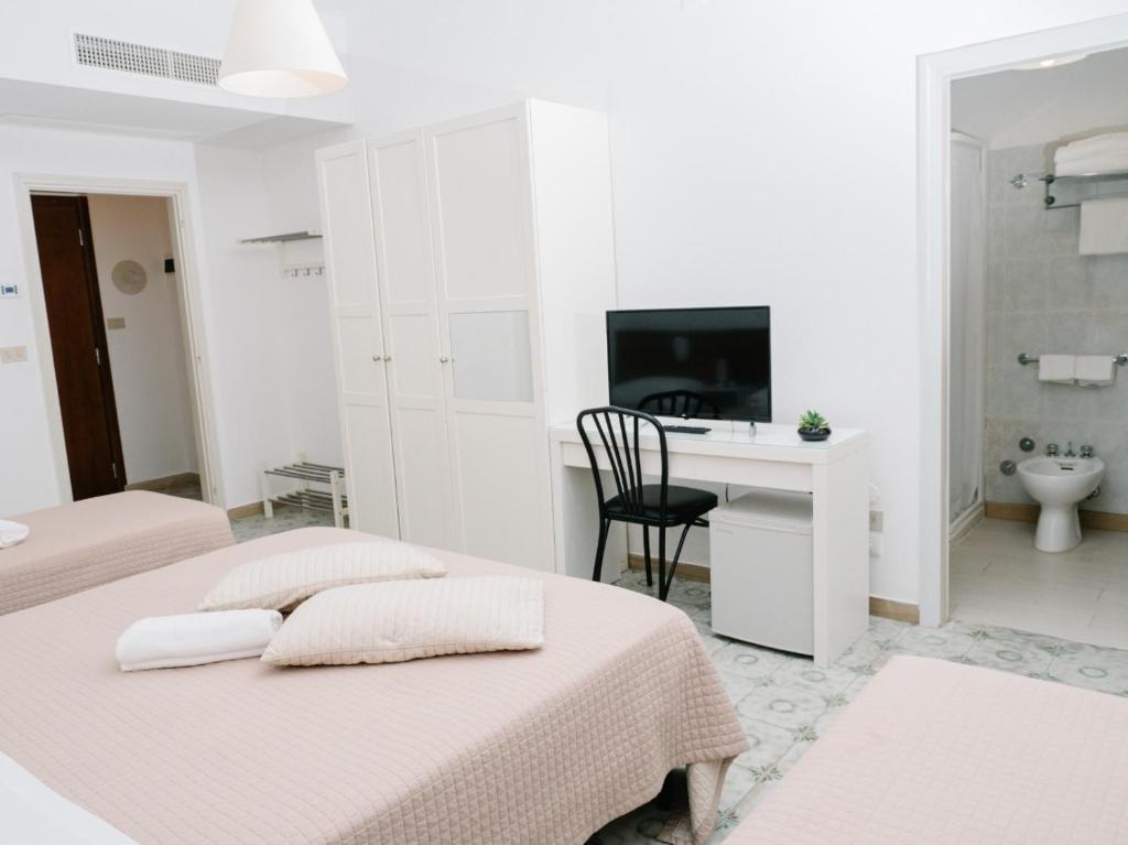 - une chambre blanche avec 2 lits et un bureau dans l'établissement Hotel Antagos, à Montesilvano