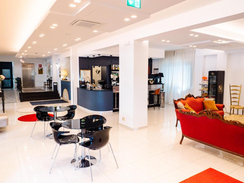 un hall d'entrée avec un canapé rouge, une table et des chaises dans l'établissement Hotel Antagos, à Montesilvano