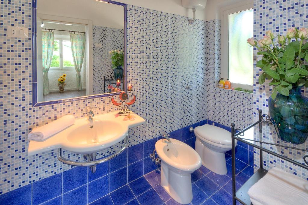 La salle de bains est pourvue de carrelage bleu, d'un lavabo et de toilettes. dans l'établissement Villaggio Turistico Internazionale, à Porto Recanati