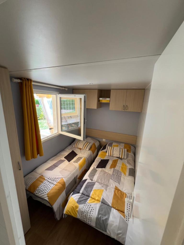 deux lits dans une petite pièce avec une fenêtre dans l'établissement Mobil home au camping 5 étoiles à Deauville, à Saint-Arnoult