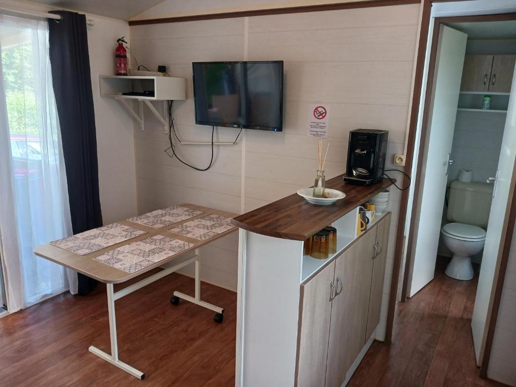 Cette petite chambre dispose de toilettes et d'une télévision murale. dans l'établissement Mobil'home, à Thiviers