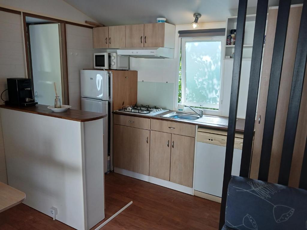 une petite cuisine avec un réfrigérateur et un évier dans l'établissement Mobil'home, à Thiviers