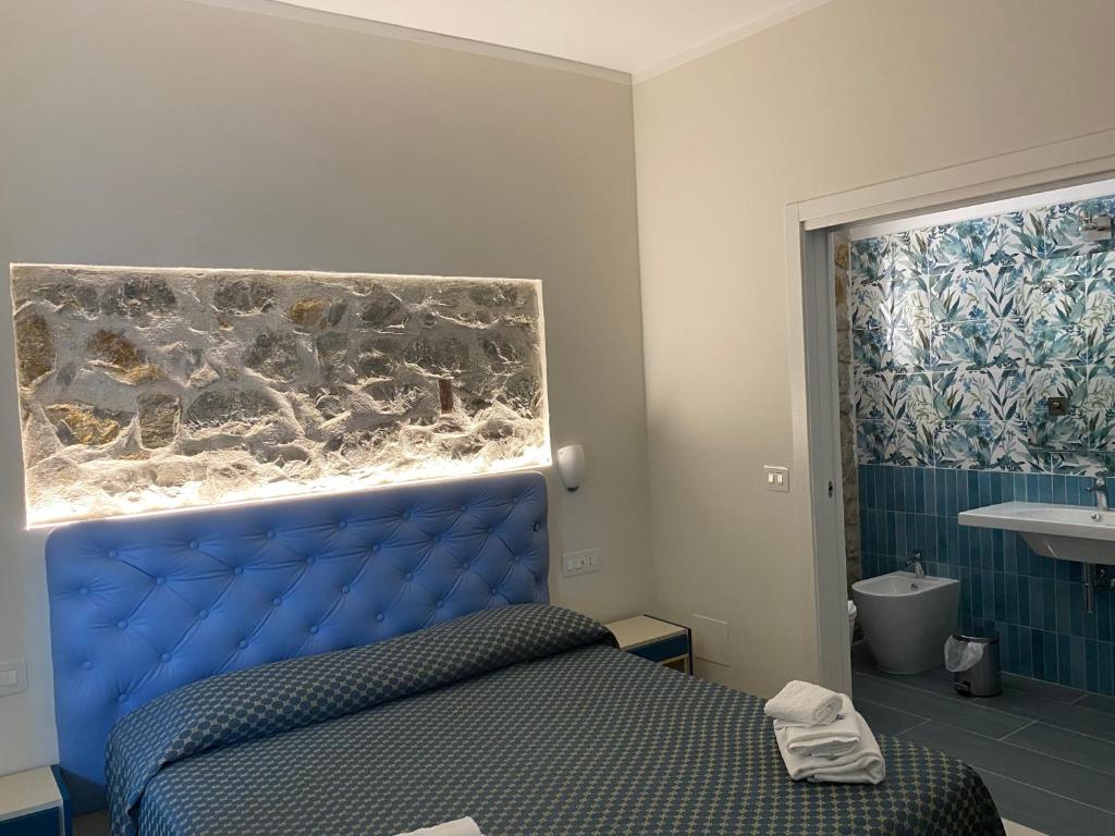 - une chambre avec un lit bleu et une salle de bains dans l'établissement Cinquestelle Albergo del centro storico, à Palinuro