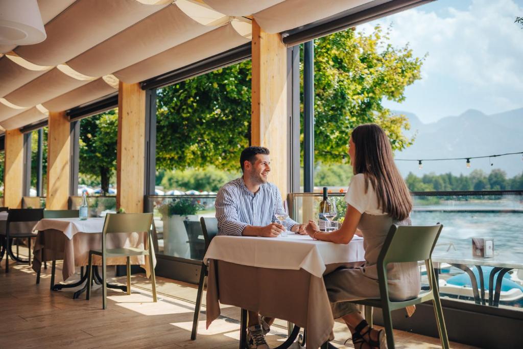 un homme et une femme assis à une table dans un restaurant dans l'établissement Parc Hotel Du Lac, à Levico Terme