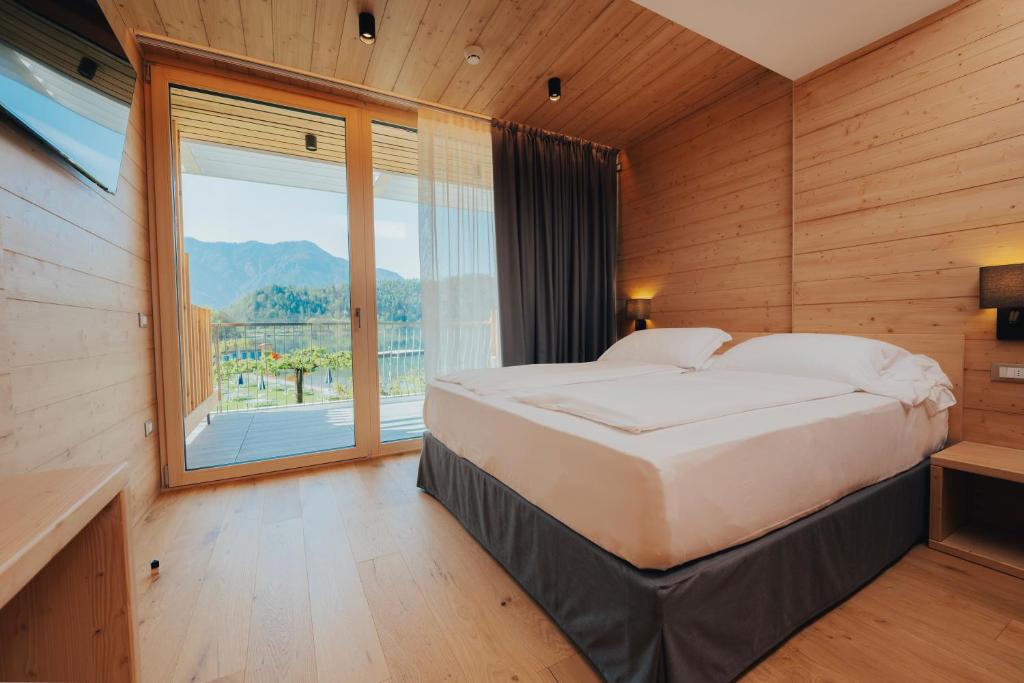 une chambre avec un grand lit et une grande fenêtre dans l'établissement Parc Hotel Du Lac, à Levico Terme