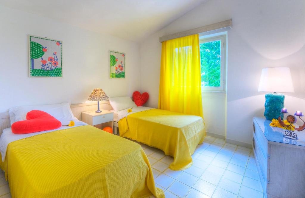 - une chambre avec 2 lits avec des draps jaunes et une fenêtre dans l'établissement Villaggio Riva Musone, à Porto Recanati