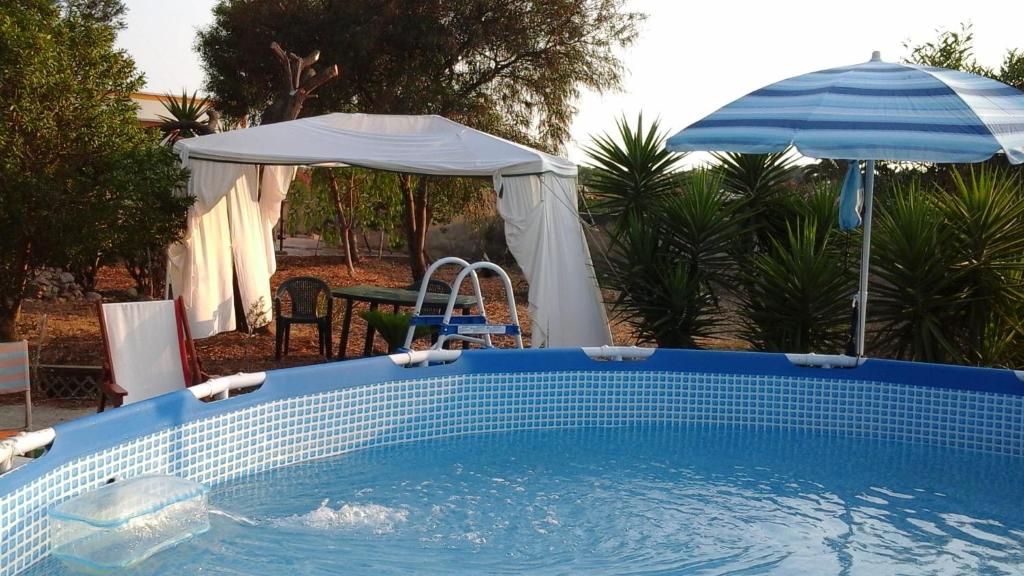 une piscine bleue avec un parasol et une table et un parasol dans l'établissement Villa Il Giardino con Piscina a soli 350 mt dalla Spiaggia di Punta Prosciutto, à Punta Prosciutto