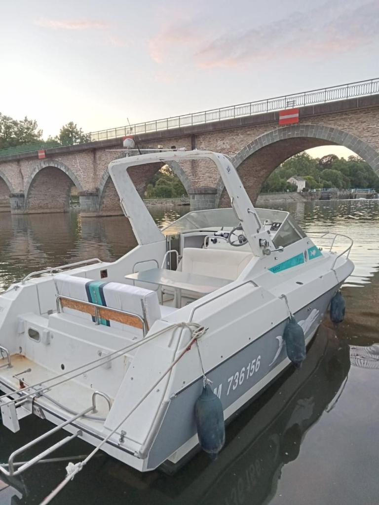 un bateau blanc dans l'eau près d'un pont dans l'établissement Bateau-gîte sur le halage de la Mayenne, à LʼHuisserie