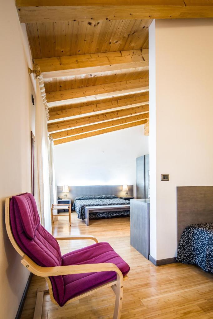 - un salon avec un fauteuil violet et un canapé dans l'établissement Hotel La Pergola, à Lignano Sabbiadoro