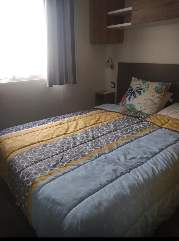- une chambre avec un lit doté d'une couverture jaune et bleue dans l'établissement Siblu le Montourey frejus, à Fréjus