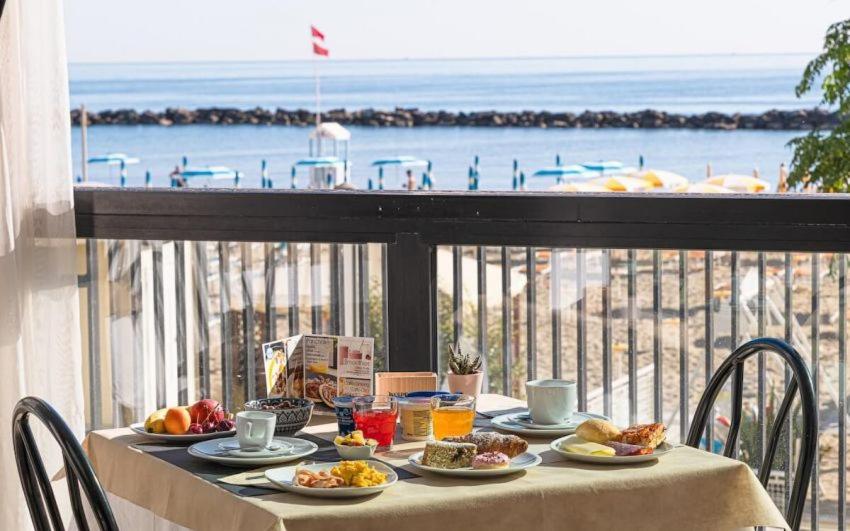 une table avec de la nourriture sur un balcon avec vue sur l'océan dans l'établissement Hotel Continental, à Bellaria-Igea Marina
