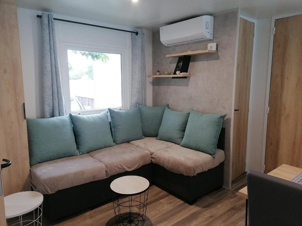 un salon avec un canapé et une fenêtre dans l'établissement Mobil home 2 chambres camping 4 étoiles vias, à Vias