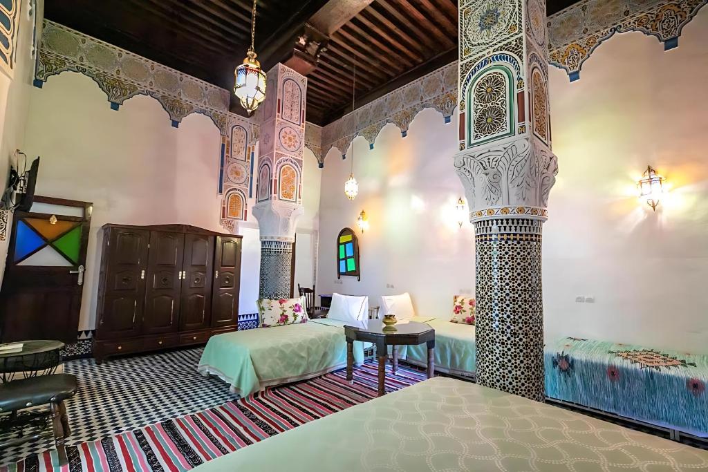 une chambre avec deux lits et une table dans une pièce dans l'établissement Riad Mounana fez luxurious palace & spa, à Fès