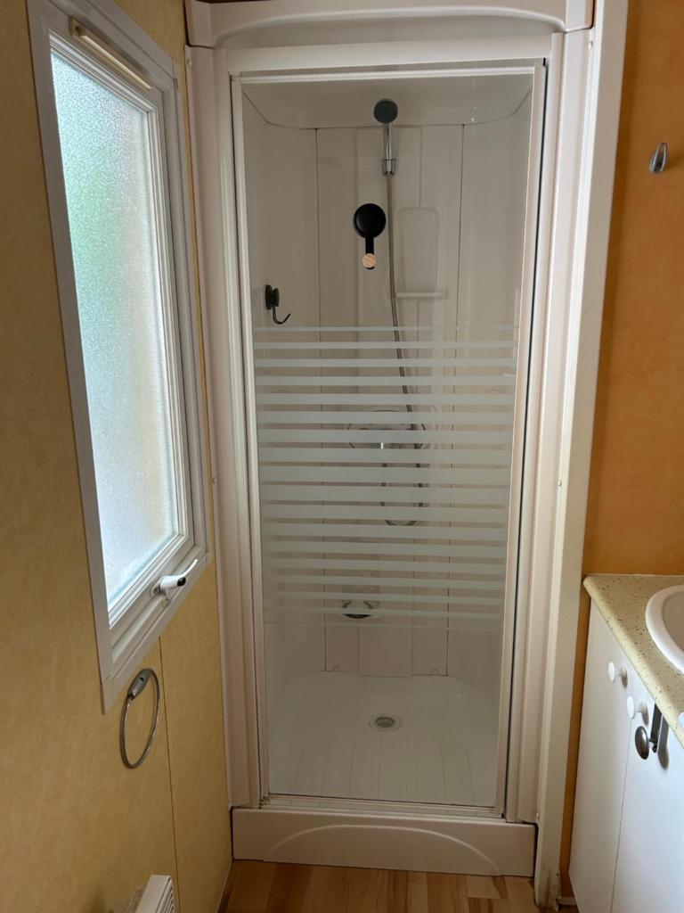 - une salle de bains pourvue d'une douche en verre à côté d'une fenêtre dans l'établissement mobil home à louer, à Thiviers
