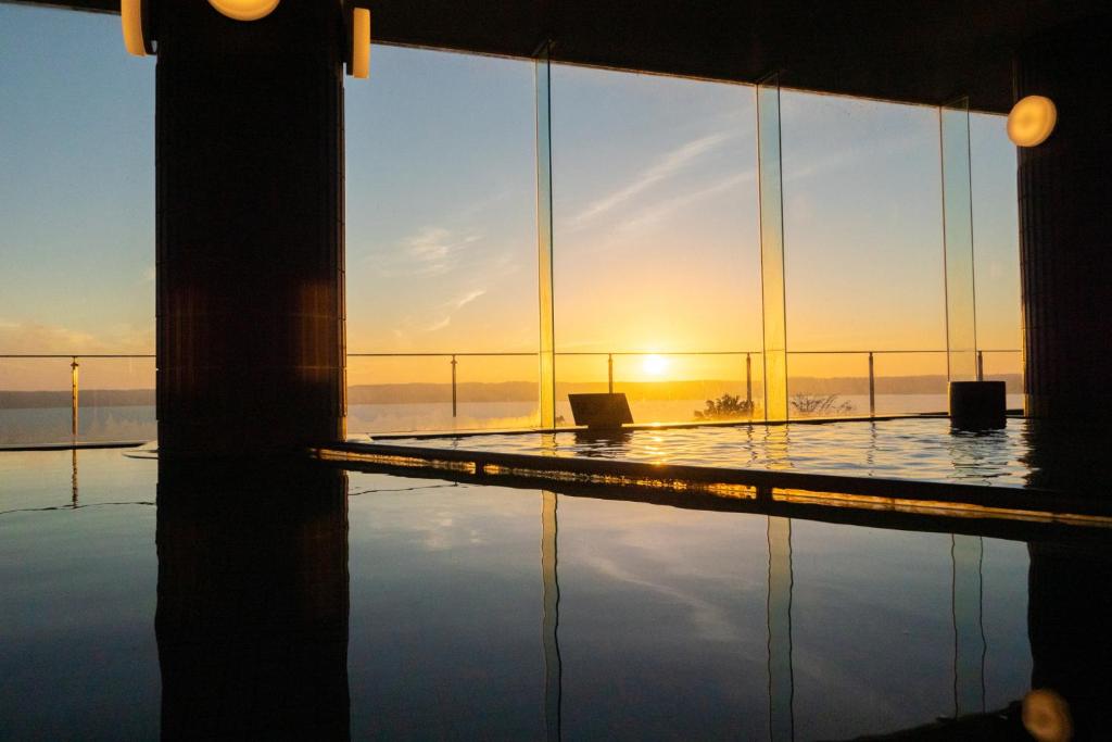 - une vue sur la piscine et le coucher de soleil en arrière-plan dans l'établissement KAMENOI HOTEL Itako, à Itako