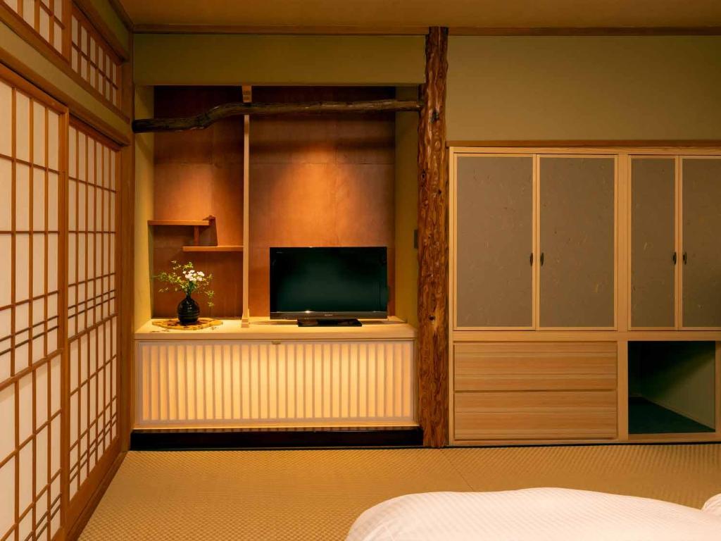 - une chambre avec une télévision sur une étagère et une armoire dans l'établissement Ryoso Yufuin Yamadaya, à Yufu