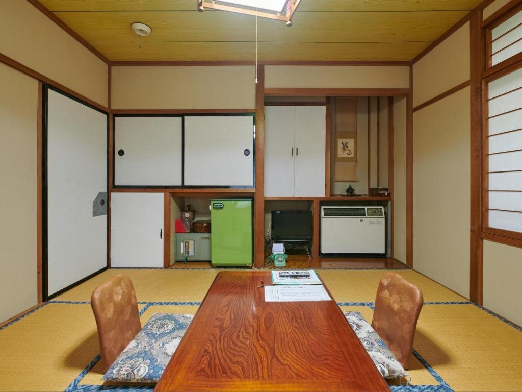une salle à manger avec une table et des chaises et une cuisine dans l'établissement Tabist Ryokufuen Kiyoharu, à Takayama