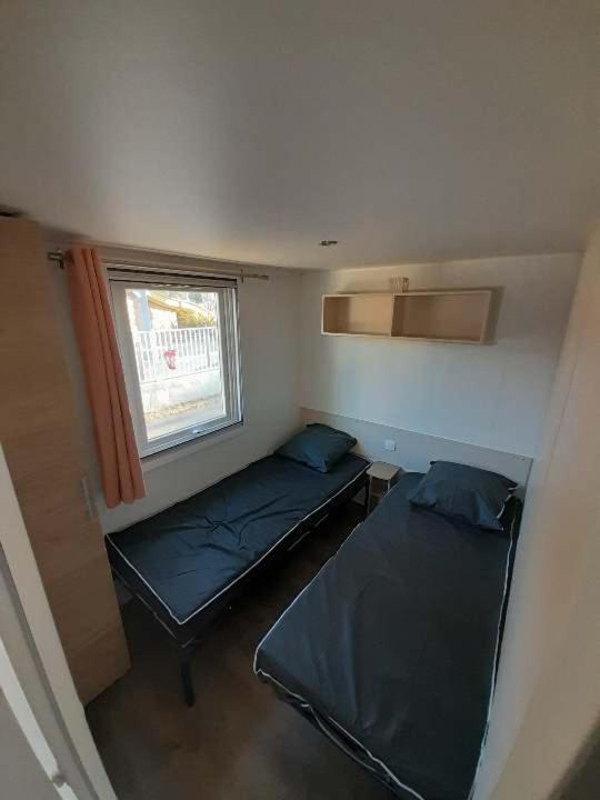 une petite chambre avec deux lits et une fenêtre dans l'établissement Mobil-Home VO42 Camping La Carabasse VIAS-Plage, à Vias 30 autres photos