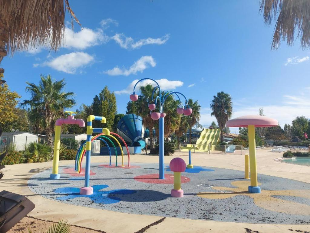 - une aire de jeux avec différents équipements de jeux colorés dans un parc dans l'établissement Mobil-Home VO42 Camping La Carabasse VIAS-Plage, à Vias