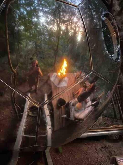un reflet d'un groupe de personnes avec un feu dans un miroir dans l'établissement Mirror globe Kandasphere, à Saint-Gervais-les-Bains