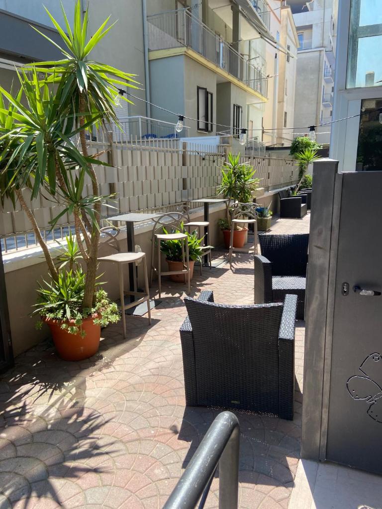 un patio avec des chaises, des tables et des plantes en pot dans l'établissement Hotel Fortuna, à Chioggia