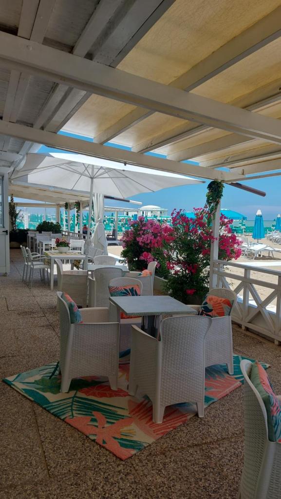 d'une terrasse avec des tables et des chaises sur la plage. dans l'établissement Albergo Regina, à Senigallia