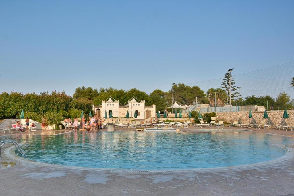 une grande piscine avec un complexe en arrière-plan dans l'établissement Hotel Thàlas Club, à Torre dell'Orso