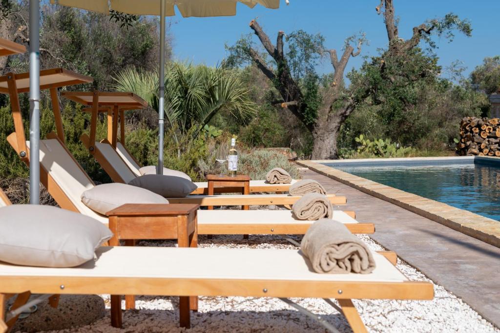 - une piscine avec des chaises longues et un parasol dans l'établissement Dimora Donnagnora, à Ostuni