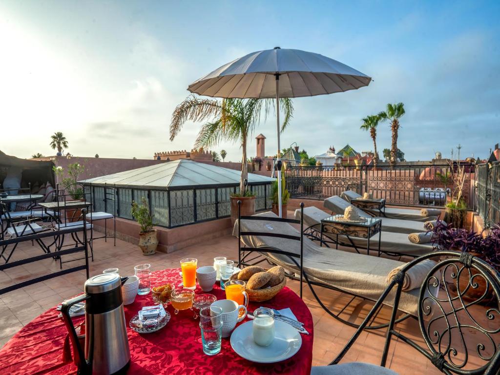 - une table avec de la nourriture et un parasol sur la terrasse dans l'établissement Riad dar ennakhla, à Marrakech