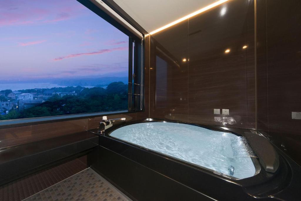 La salle de bains est pourvue d'une baignoire et d'une grande fenêtre. dans l'établissement Ise-Shima Ohtaya Healing Stay, à Toba