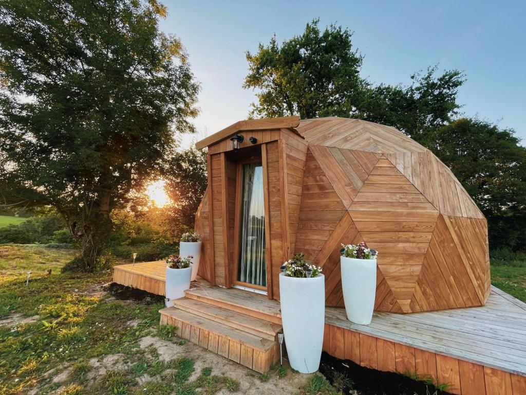 une maison en bois avec deux plantes en pot sur une terrasse dans l'établissement L'étoile de Baynes, à Cerisy-la-Forêt 11 autres photos