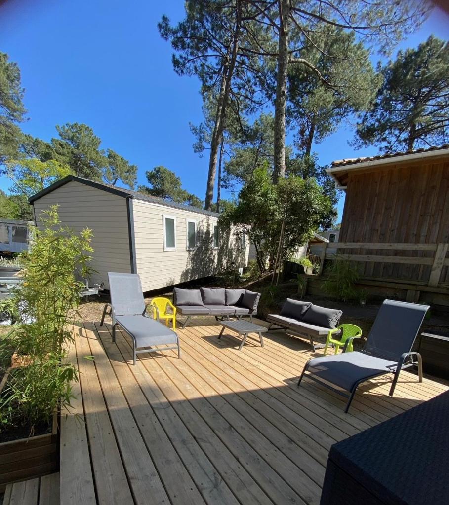 un patio avec des chaises et des canapés sur une terrasse en bois dans l'établissement La cabane des pins, à Lège-Cap-Ferret
