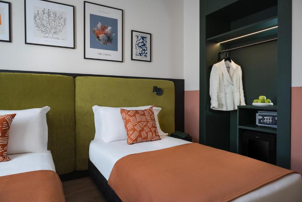 - une chambre avec 2 lits et un manteau suspendu au mur dans l'établissement DuoMo Hotel, à Rimini