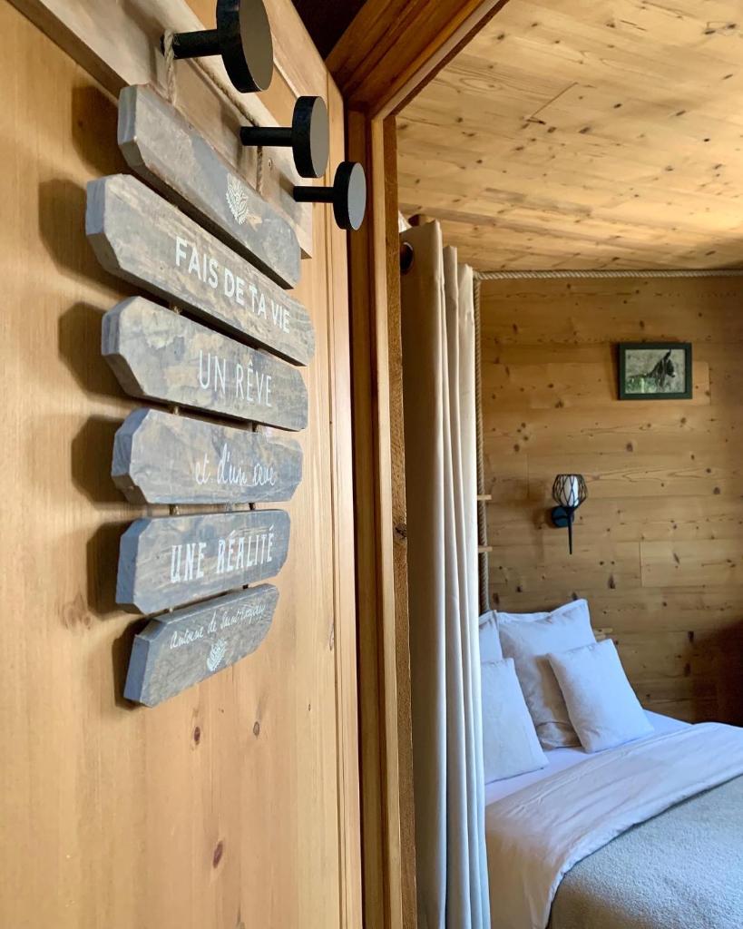 un panneau sur un mur à côté d'un lit dans une chambre dans l'établissement Cabane dans les Arbres de Valmo'Insolite, à Valmorel