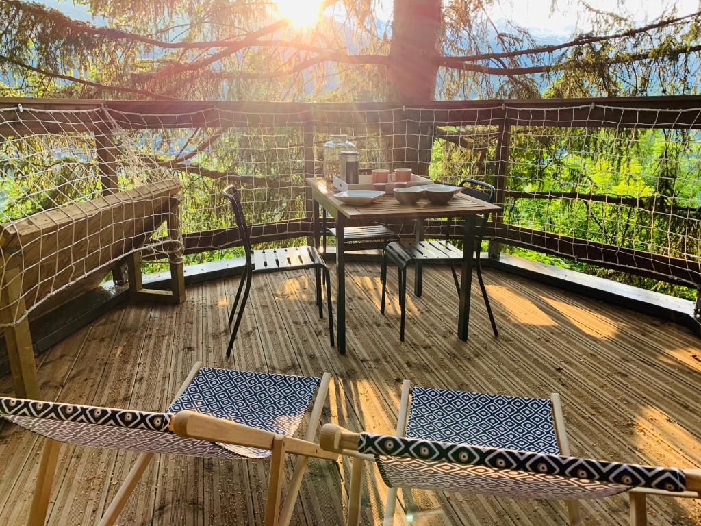 un patio avec une table et des chaises sur une terrasse dans l'établissement Cabane dans les Arbres de Valmo'Insolite, à Valmorel