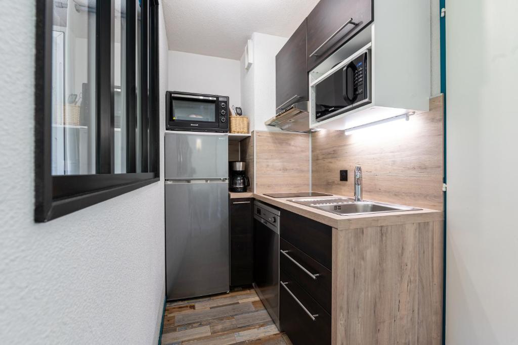 une petite cuisine avec un évier et un réfrigérateur dans l'établissement Appartement 6 personnes, à Saint-François-Longchamp