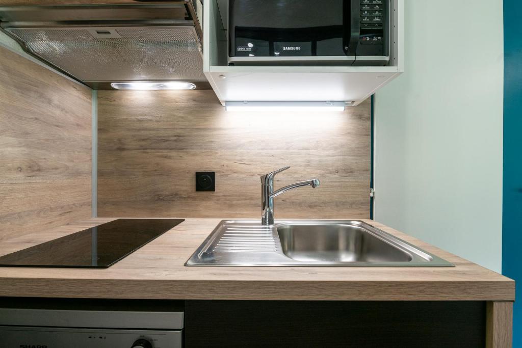 une cuisine avec un évier et un micro-ondes dans l'établissement Appartement 6 personnes, à Saint-François-Longchamp