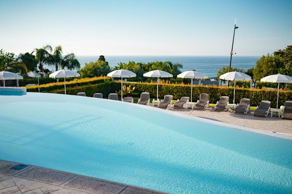 une grande piscine avec chaises et parasols dans l'établissement Sentido Michelizia Tropea Resort, à Tropea