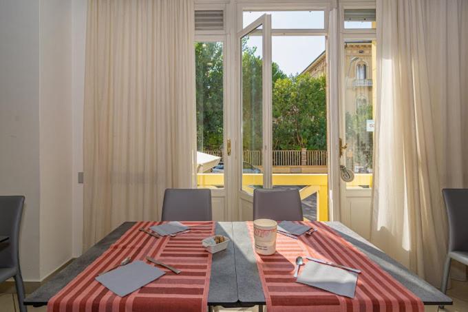 une table de salle à manger avec des chaises et une grande fenêtre dans l'établissement Hotel Playa, à Viareggio