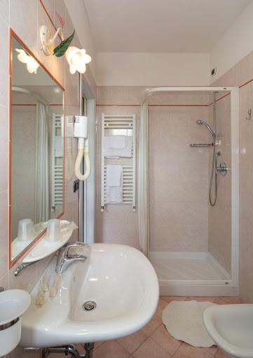 une salle de bain blanche avec lavabo et douche dans l'établissement Hotel Playa, à Viareggio