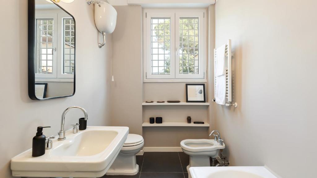 une salle de bain avec un lavabo, des toilettes et un miroir dans l'établissement ANTICO CERASO 10, Emma Villas, à Grottaferrata 25 autres photos