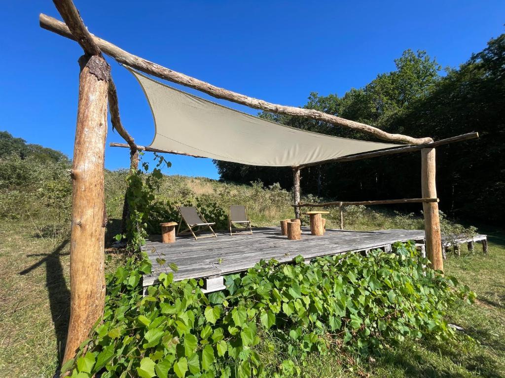 - un hamac sur une terrasse en bois avec 2 chaises dans l'établissement La tente Chemin d'étoiles, à Soturac