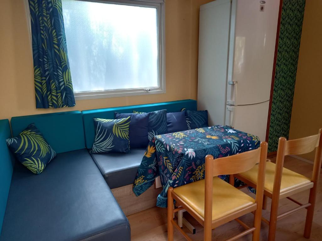 un salon avec un canapé bleu et une table dans l'établissement Mobil Home climatisé avec terrasse dans camping l'Escale, calme à 900m de la plage, à Agde