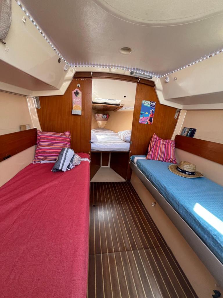 une petite chambre avec deux lits dans un bateau dans l'établissement Voilier et plage, au Cap d'Agde