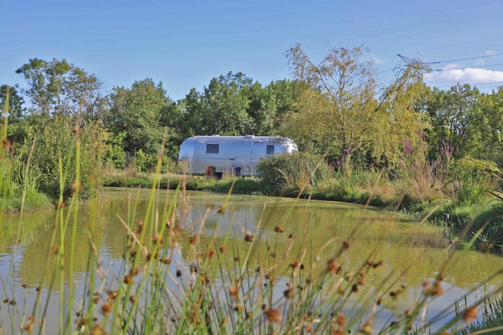 une remorque garée à côté d’une masse d’eau dans l'établissement Caravane Airstream bord de lac, à Saint-Loubès