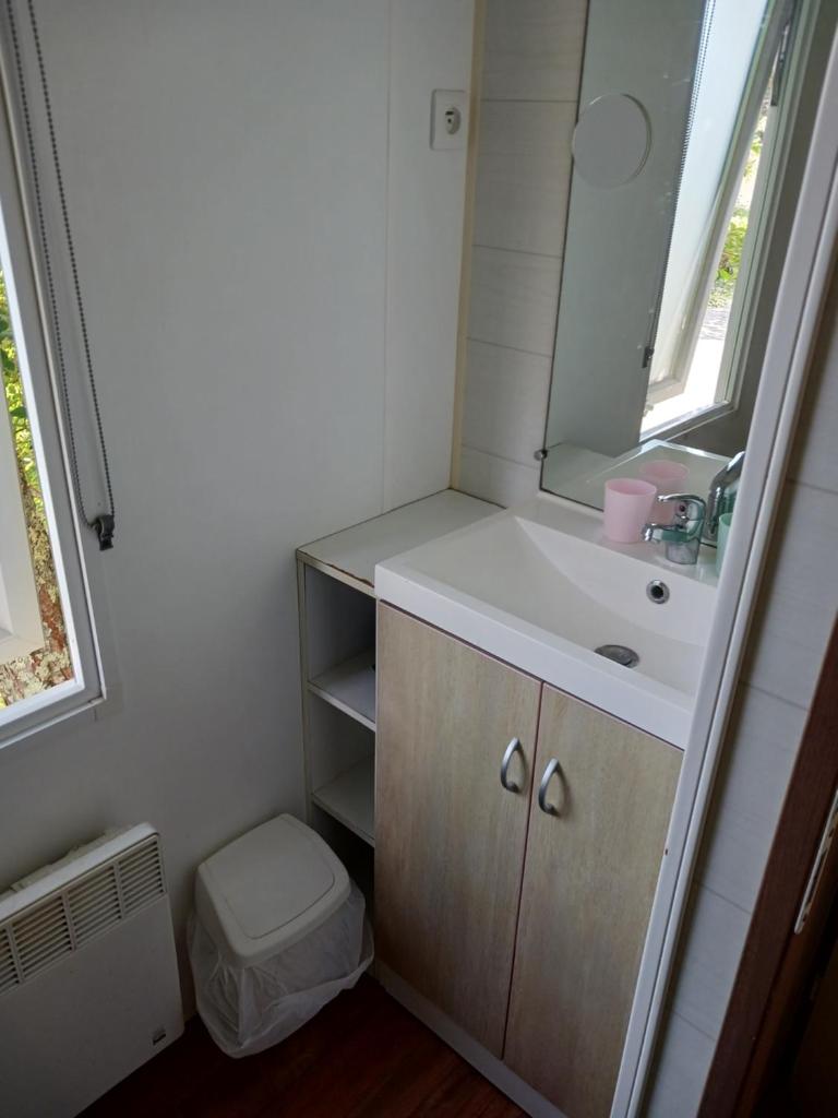 une salle de bain avec un lavabo et un miroir dans l'établissement Mobil'home, à Thiviers
