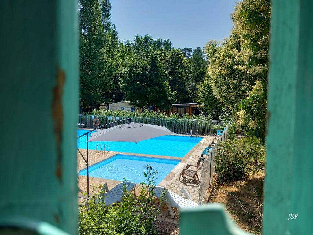 - une piscine avec un parasol et des chaises dans l'établissement Mobil-home Riviera, à Vaudreuille