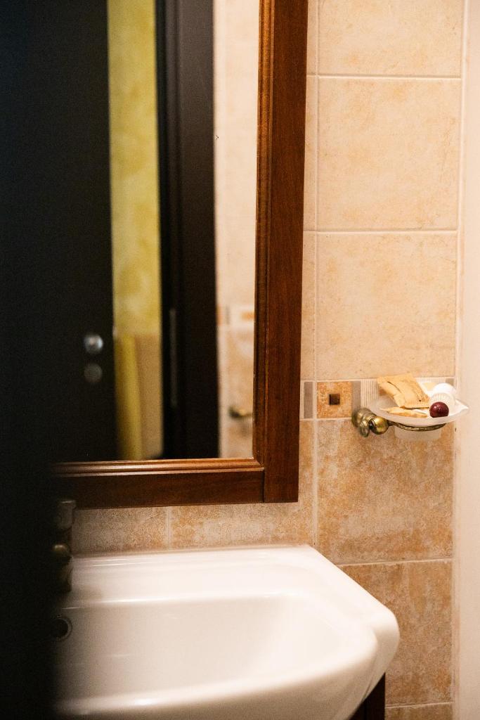 une salle de bain avec un lavabo blanc et un miroir dans l'établissement Mannu Hotel, à Bosa