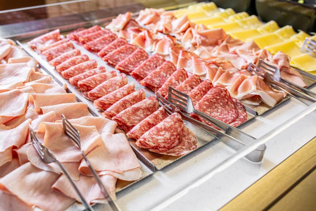 une vitrine avec différents types de viandes et de fromages dans l'établissement Hotel La Pergola, à Lignano Sabbiadoro 31 autres photos